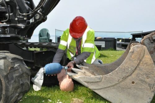 Mannequin de formation à la réanimation sous un engin de chantier